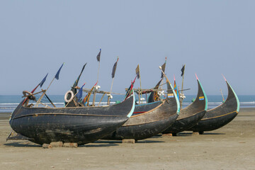 Four traditional wooden fishing boats known as moon boats resting dry on a beach near Cox's Bazar in southern Bangladesh