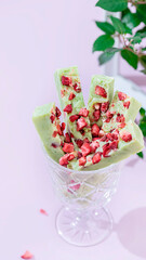 Fudge, sweet candies, handmade dessert made of white chocolate, matcha tea and strawberries on a bright background.