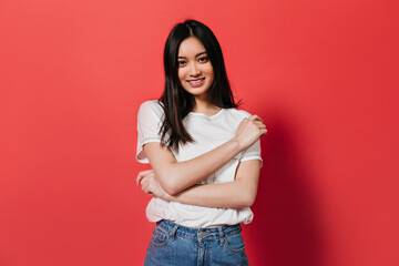 Brown-eyed woman in cotton top posing with smile on red background