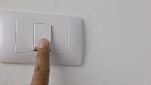 Earth Hour, Close up male hand turn off the light to saving electrical energy. Finger pushing light switch turn on or off. White switch