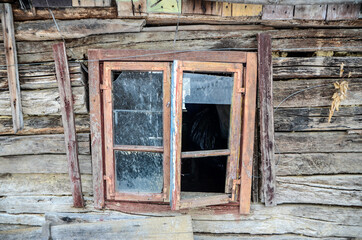 Fototapeta na wymiar Window on traditional wooden house in village. Old wooden hut covered with a snow in winter. 