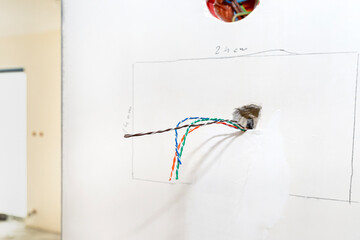Colorful videophone cables sticking out of house wall in room.