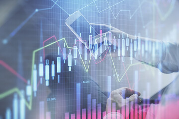 Double exposure of man's hands holding and using a digital device and forex graph drawing. Financial market concept.