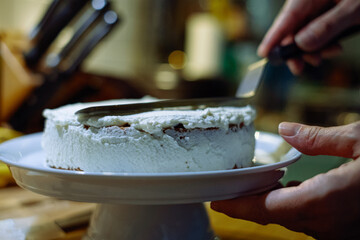 person prepairing cake with whipped cream on table