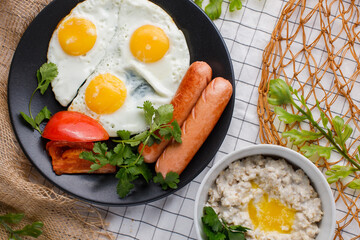 English breakfast. fried eggs with sausages and tomatoes and oatmeal with butter