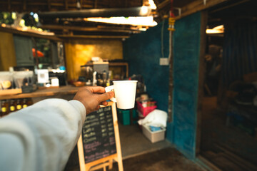 Paper coffee cups in hand at a coffee rustic shop