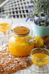 rich teapot of citrus tea with orange and lemon on a light background with two cups of tea