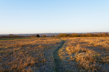 Narrow winding path across a frosty hillside at sunrise