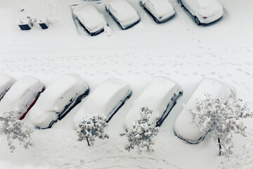top view of group of cars covered by snow and footprints in the snow
