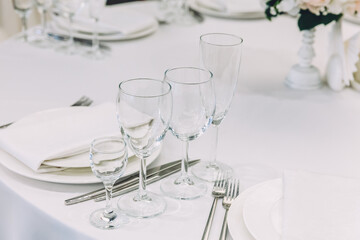 Fancy table set for dinner with napkin glasses in restaurant, luxury interior background. Wedding elegant banquet decoration and items for food arranged by catering service on white tablecloth table.