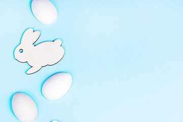 Top view flat lay funny wooden Easter Bunny with eggs as symbols of a holiday with copy space on light pink background.