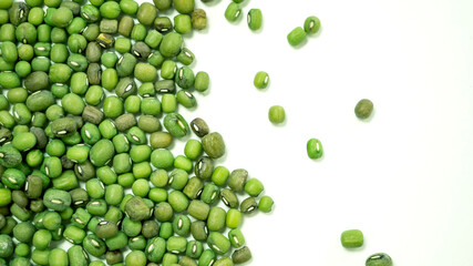 Scattered green grains of Mung Beans on a white background, top view. Healthy vegetarian food. Food background concept.