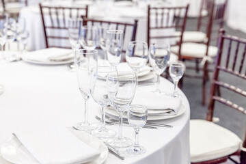 Fancy table set for dinner with napkin glasses in restaurant, luxury interior background. Wedding elegant banquet decoration and items for food arranged by catering service on white tablecloth table.
