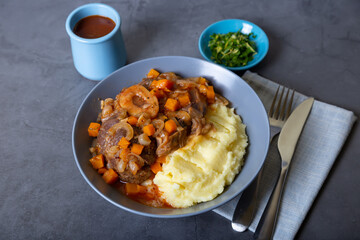 Ossobuco. Veal (beef) shanks with mashed potatoes, gremolata and sauce. Traditional Italian dish. Close-up.