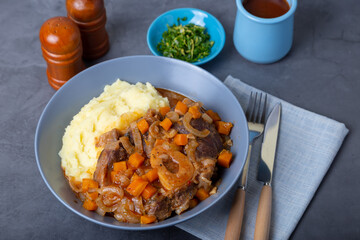 Ossobuco. Veal (beef) shanks with mashed potatoes, gremolata and sauce. Traditional Italian dish. Close-up.