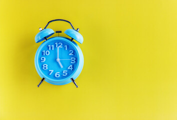 Blue alarm clock on yellow background. Top view. Copy space for text.