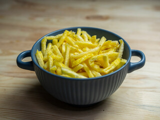 Freshly cooked French fries. One serving of French fries on a wooden table in a bar.