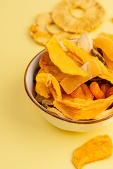 Ceramic bowl with assorted vegan jerky on yellow background, top view