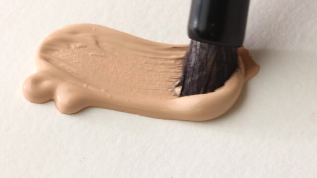 beige smear of tonal foundation cream close up, smudge with a brush, beautiful pastel texture, cosmetic product for make up
