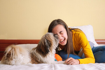 Young woman with her pet dog playing on the bed