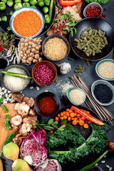 Asian raw vegan food, grain, seeds and vegetables on dark background