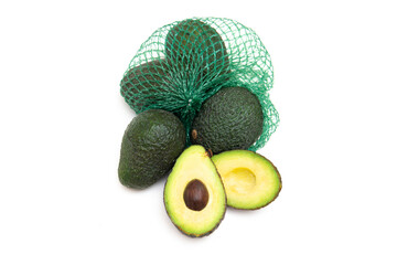 Fresh Hass avocados in a green mesh bag isolated on white. One avocado fruit is cut open.