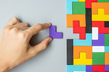 hand connecting geometric shape block with colorful wood puzzle pieces. logical thinking, business...