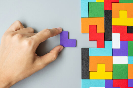 hand connecting geometric shape block with colorful wood puzzle pieces. logical thinking, business logic, Conundrum, decision, solutions, rational, mission, success, goals and strategy concepts
