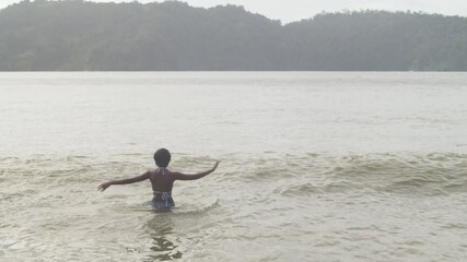 Girl dancing and enjoying herself in the waters of the north coast of Trinidad - Powered by Adobe