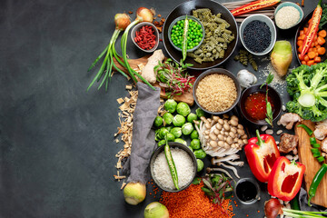 Asian raw vegan food, grain, seeds and vegetables on dark background