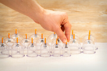 Hand of massage therapist taking vacuum cups from the table before cupping procedures