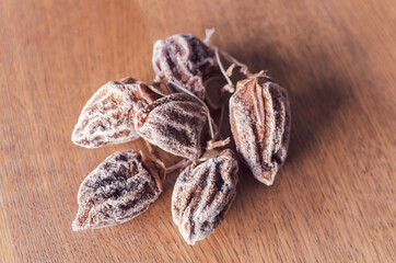 A bunch dried persimmons fruits suspending on rope on the wooden  background. Horizontal frame, selective focus.
