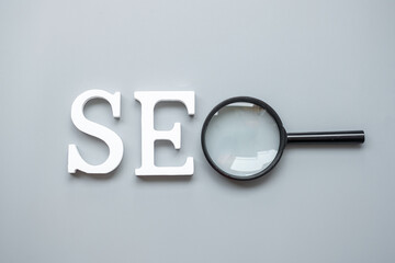 SEO (Search Engine Optimization) text and magnifying glass on gray background. Idea, Vision,...