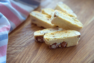 Sweet biscotti cookies with nuts and a striped kitchen towel on wooden background. Side view
