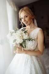 Naklejka premium Beautiful bride portrait in wedding dress near window