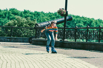 Very beautiful teenager girl rides on roller skates in a summer park in the city