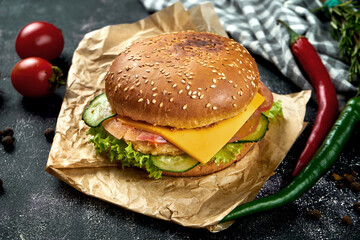 Juicy burger with chicken, tomatoes, cheese and crispy onions on a dark background. Chickenburger