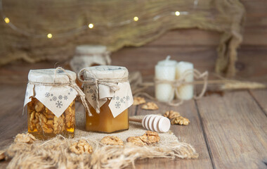 Jars of honey with nuts and orange with winter decoration paper 
