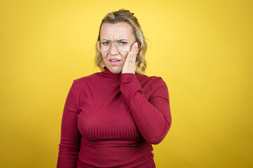 Young caucasian woman wearing casual red t-shirt over yellow background touching mouth with hand with painful expression because of toothache or dental illness on teeth