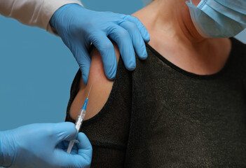 Doctor therapist revaccination elderly woman against omicron strain. Isolated on blue.