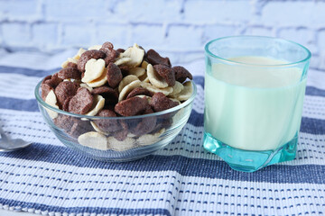 chocolate corn flakes in a bowl and milk on table 