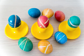 Colorful painted homemade easter eggs with modern pattern on yellow coasters on wooden table. Easter decoration, easter background.