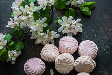 Delicious pink and white marshmallows on the table along with a blossoming branch of apple tree. Sweets.