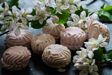 Delicious pink and white marshmallows on the table along with a blossoming branch of apple tree. Sweets.