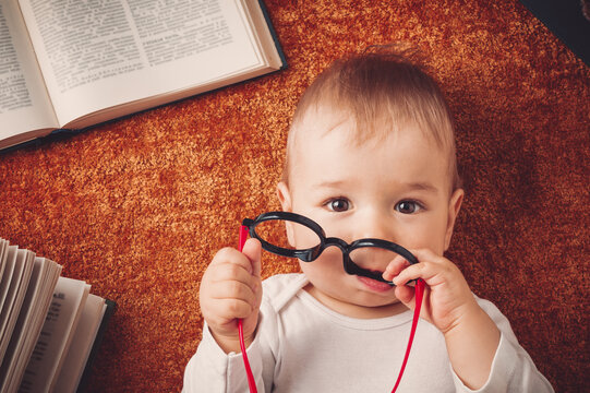 One year old baby with spectackles and books