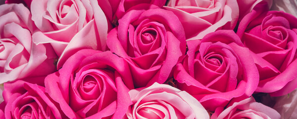Artificial red roses background top view.