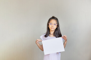 Naklejka premium Asian girl with white sheet of paper, girl holding empty blank paper, mock up blank sign for message creative design concepts.