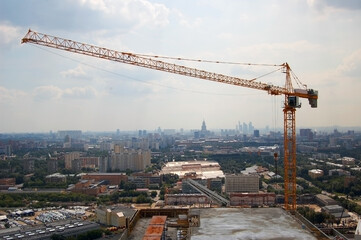 Construction crane on the construction of a high-rise building against the blue sky