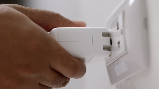 Close up male hand put on the Electric adapter smartphone or laptop plug. Electrical wires and power strips in the house