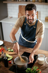 Happy man in kitchen. Young man preparing delicious food..